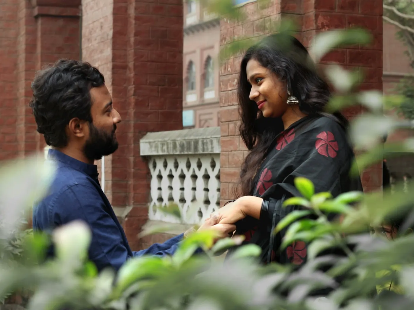A young couple in conversation in front of a carved jaali wall